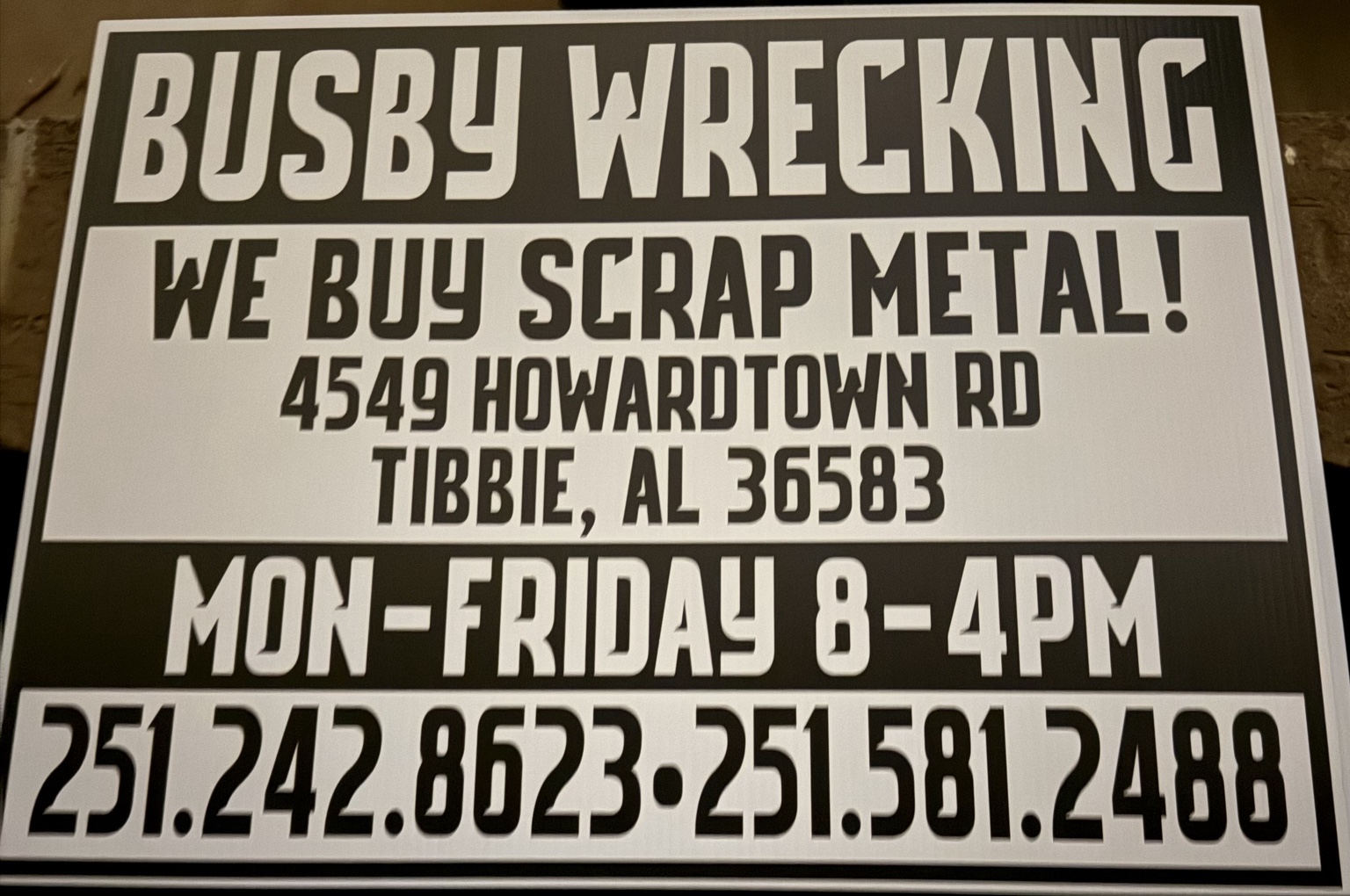 Busby Wrecking sign showing address and hours